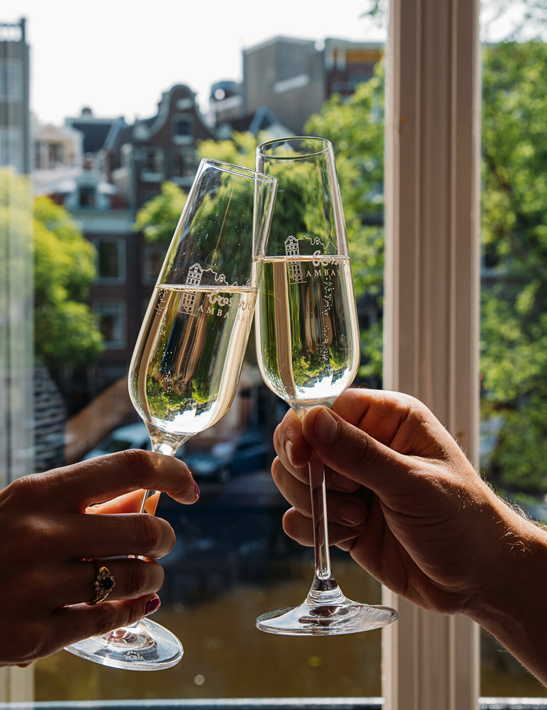 Two glasses of cava toasting in a canal view room at the ambassade hotel in amsterdam.