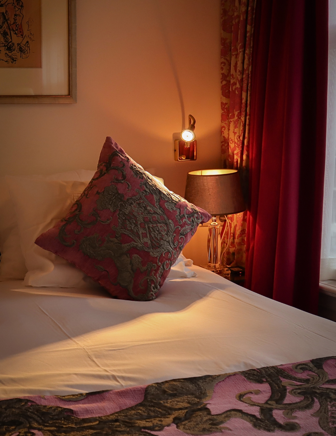 Warm bedside lamp lit next to a comfortable bed in a room at the ambassade hotel in amsterdam.