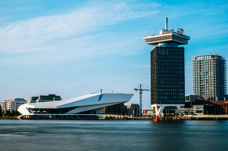 Uitzicht op de rivier het IJ in Amsterdam met boten en gebouwen aan het water.