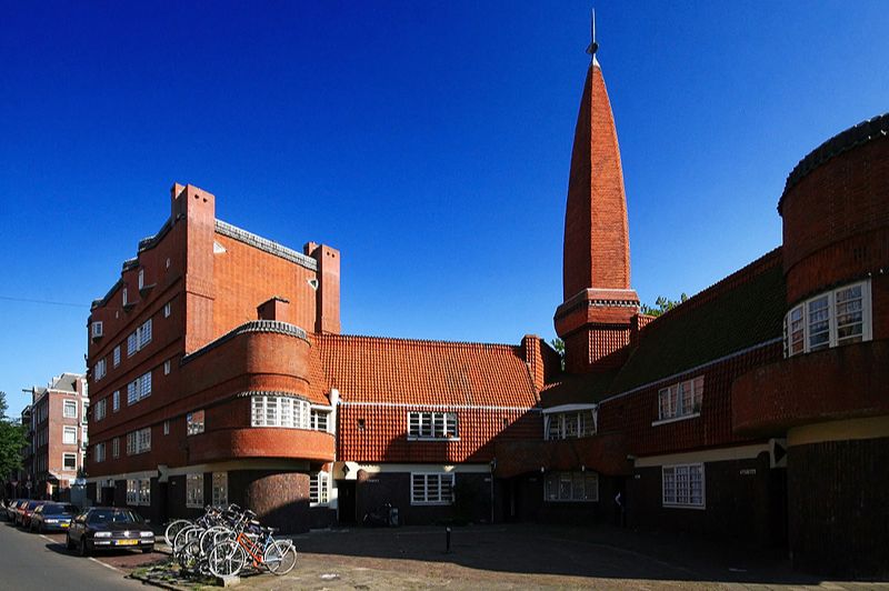 Gebouw dat de Amsterdamse School-architectuur toont met metselwerk en decoratieve details.