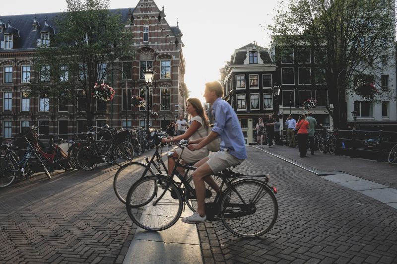Fietsers die langs het fietspad aan de gracht in Amsterdam rijden.