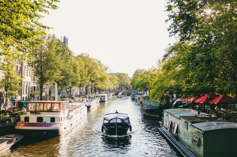 Boot die vaart langs een Amsterdamse gracht met historische gebouwen.