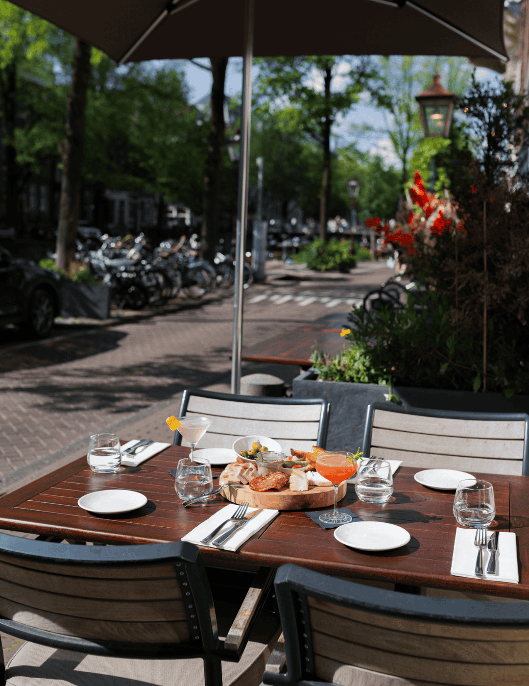 Sunlit table set for dining on the terrace at the ambassade hotel.