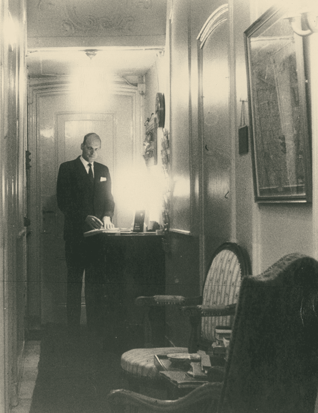 Vintage photo of staff memeber standing at the check-in desk of the ambassade hotel in amsterdam.