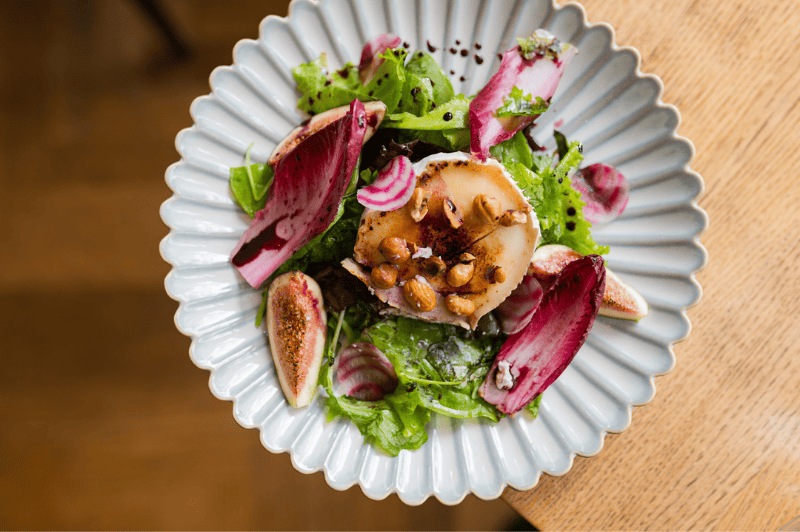 Goat cheese and fig salad served at brasserie ambassade in amsterdam, combining fresh greens with sweet figs and creamy cheese.