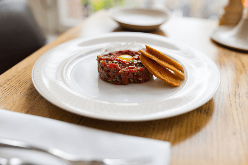 Steak tartare served at brasserie ambassade in amsterdam, presented with classic garnishes.