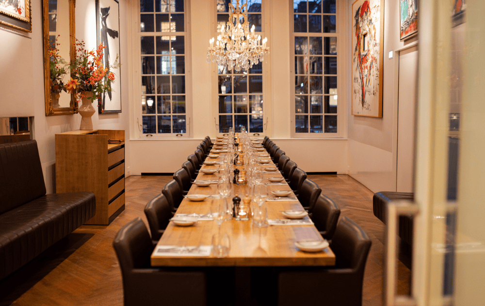 Wolvecamp lounge at brasserie ambassade in amsterdam set for private dining, with a long table and large windows letting in natural light.