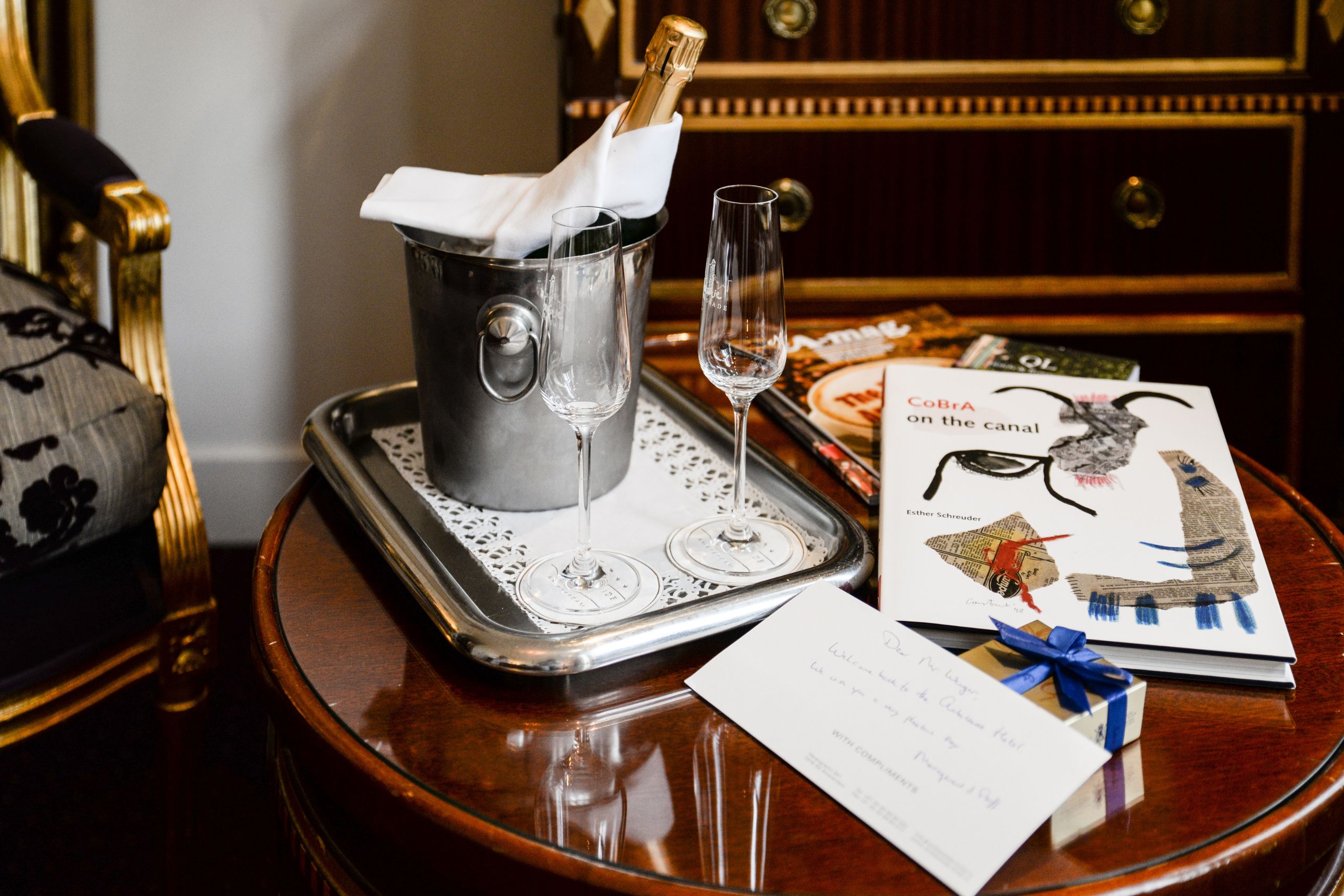 Bottle of champagne with a welcome card in a guest room at the ambassade hotel.