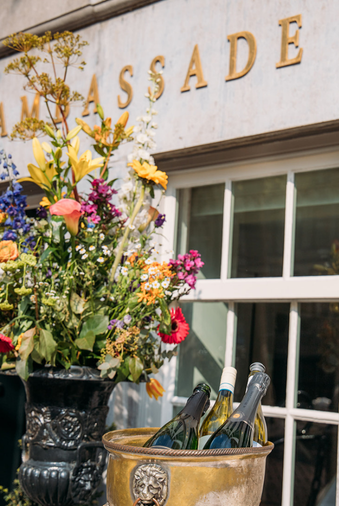 Facade of the ambassade hotel with a beautiful bouquet of flowers and a wine cooler with wine.