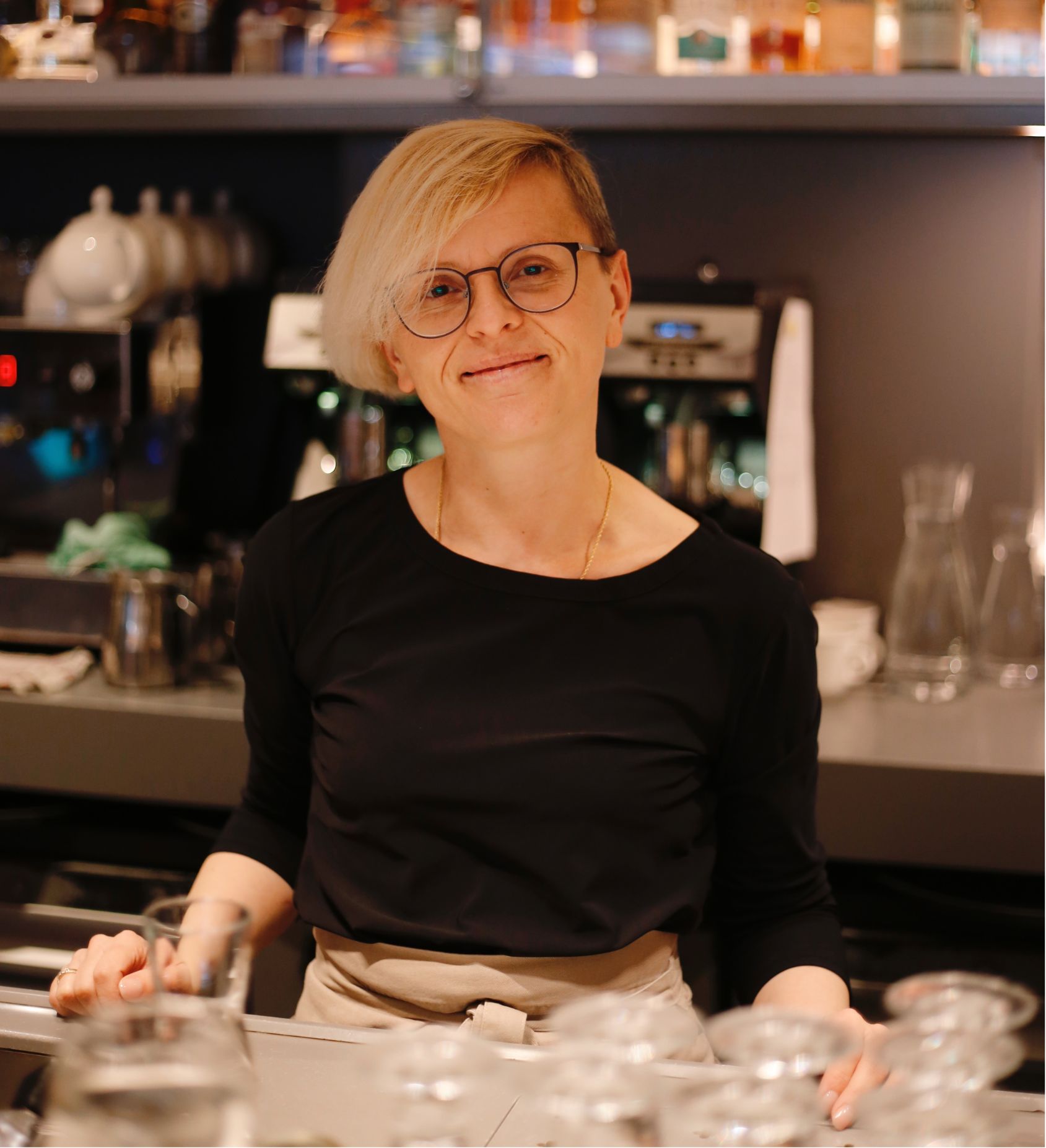 Smiling staff member standing behind the library bar at the ambassade hotel.