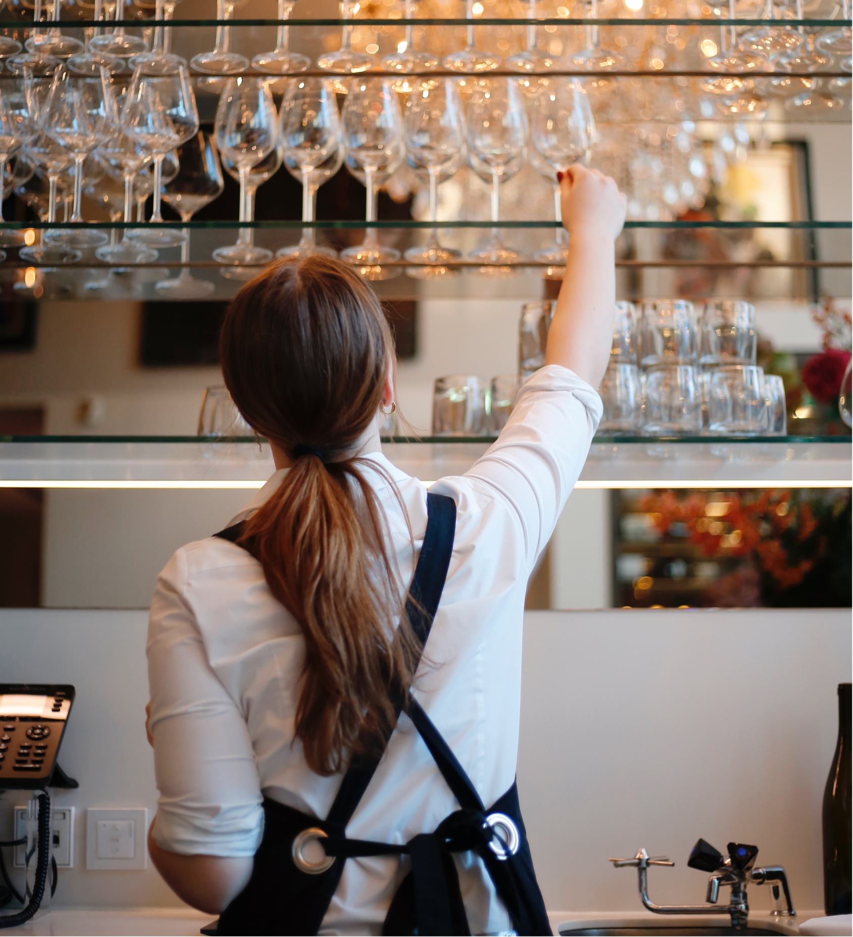 Staff member taking wine glasses at the ambassade hotel.